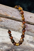 Beaded bracelet with brown and amber colored beads on a wooden surface