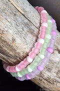 Set of three pastel-colored, glow-in-the-dark beaded bracelets on a wooden surface