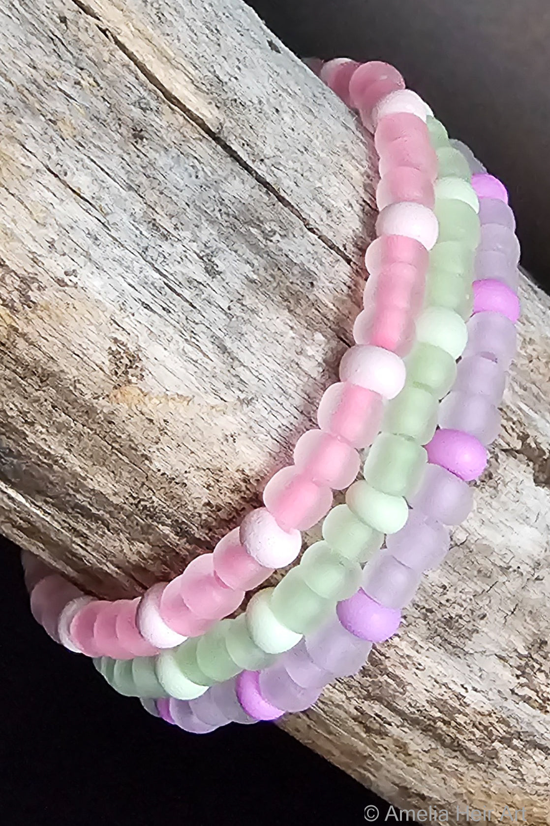 Set of three pastel-colored, glow-in-the-dark beaded bracelets on a wooden surface