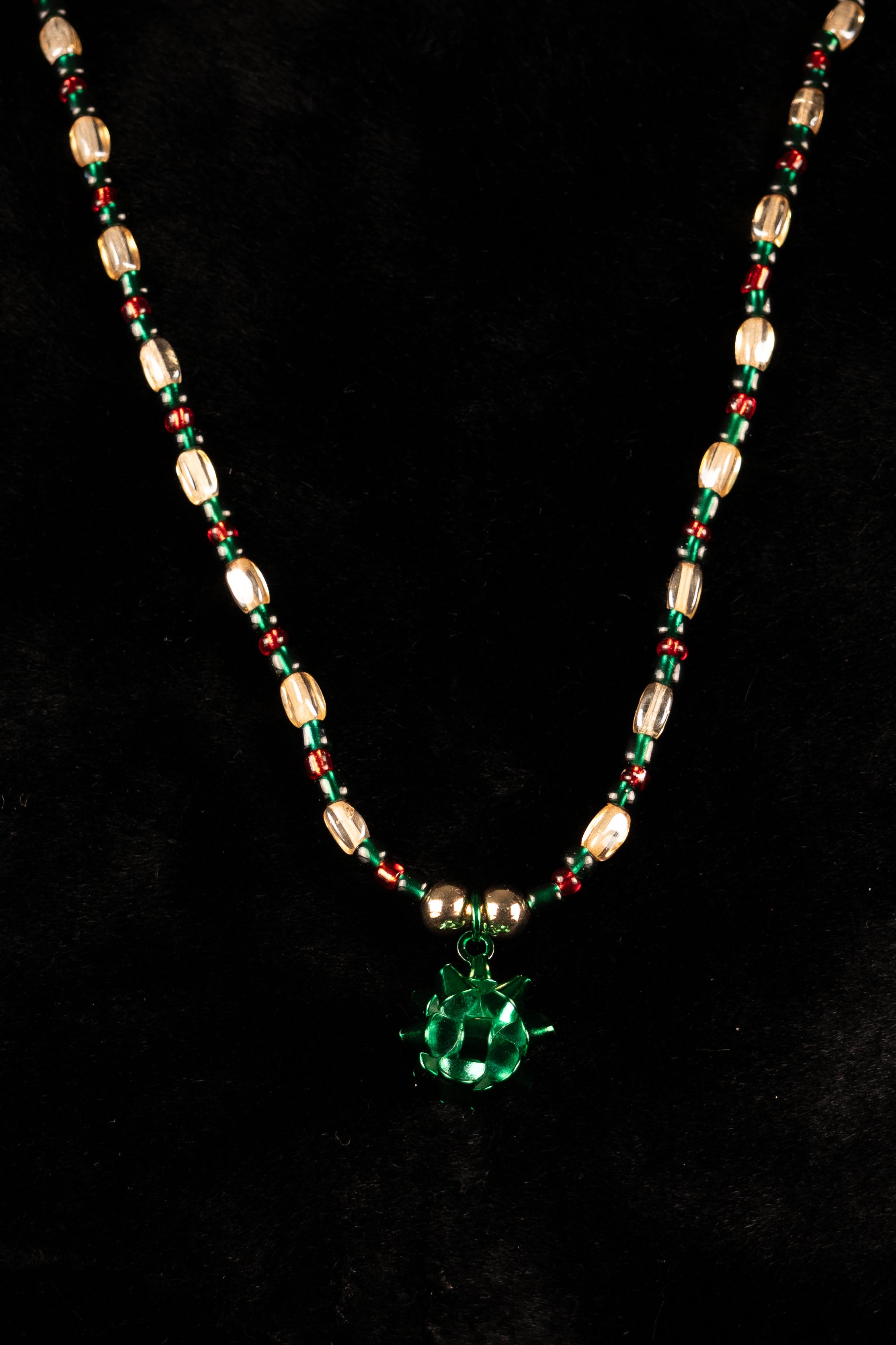 Necklace with green gift bow pendant on a black background