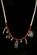 Necklace with red and white beads and silver holiday charms on a black background