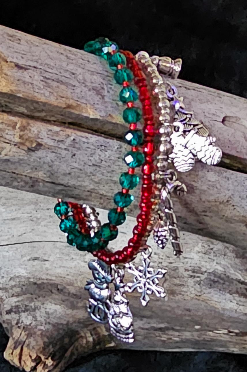 Red, green, and silver color beaded bracelets with holiday charms on a wooden surface