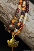 Beaded bracelet with a gold leaf charm on a wooden surface