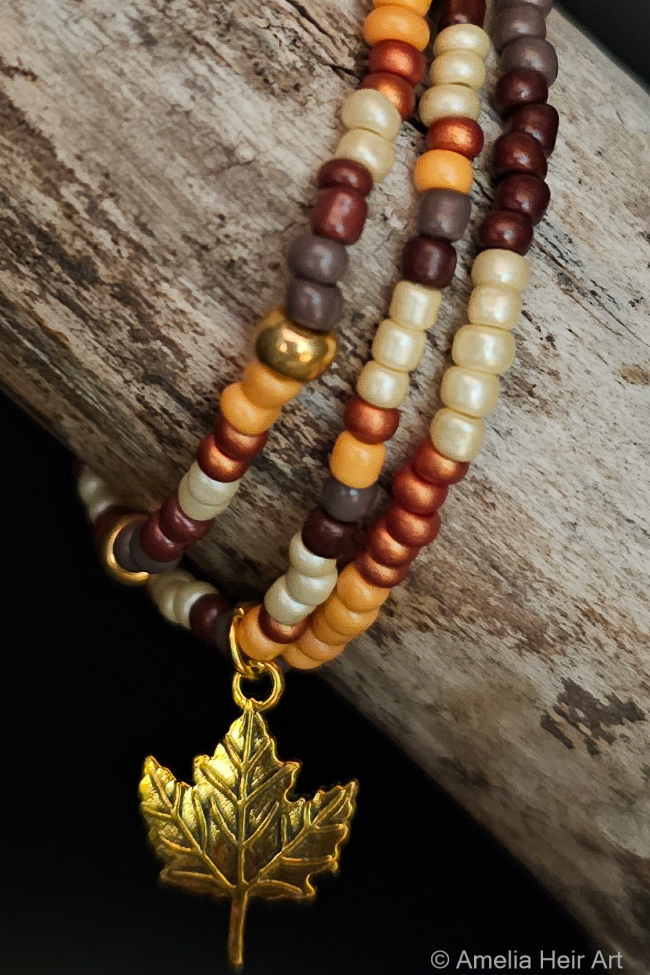 Beaded bracelet with a gold leaf charm on a wooden surface