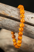 Orange beaded bracelet on a wooden branch with a blurred background