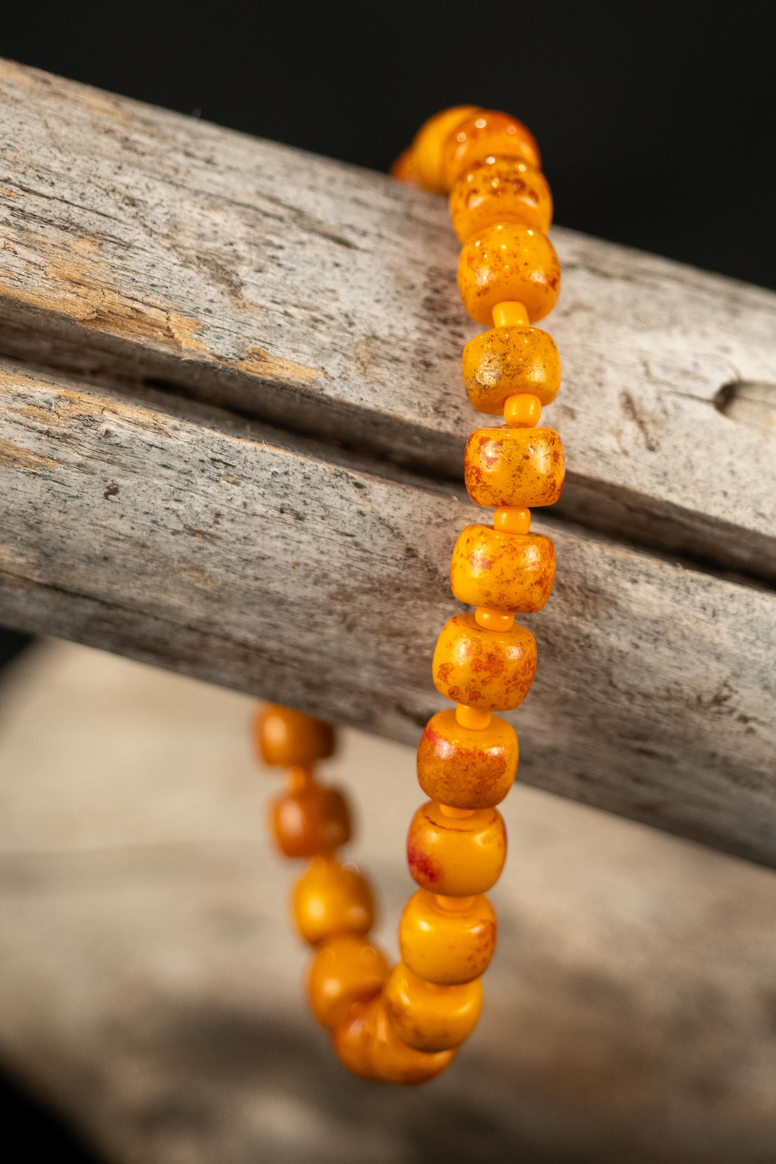 Orange beaded bracelet on a wooden branch with a blurred background