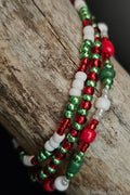 Beaded bracelets in red, green, and white on a wooden surface
