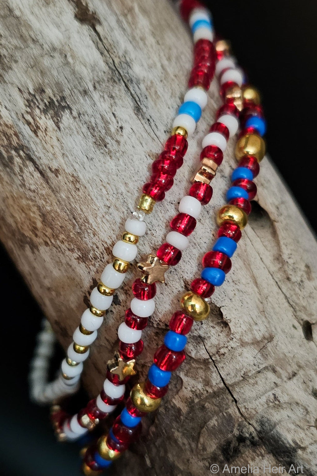 Opportunity handcrafted red, white, blue & gold beaded bracelet set with star charm on a wooden surface — Amelia Heir Art