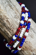 Three beaded bracelets in red, white, and blue on a wooden surface