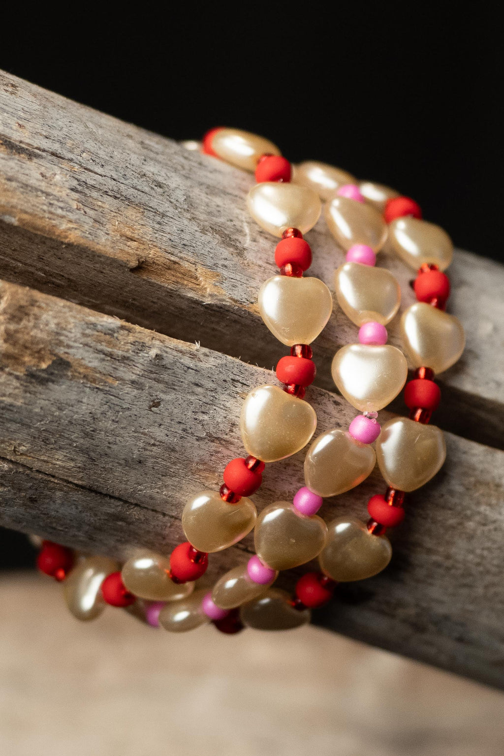 Pearl handcrafted white red and pink beaded bracelet set on a wooden surface — Amelia Heir Art