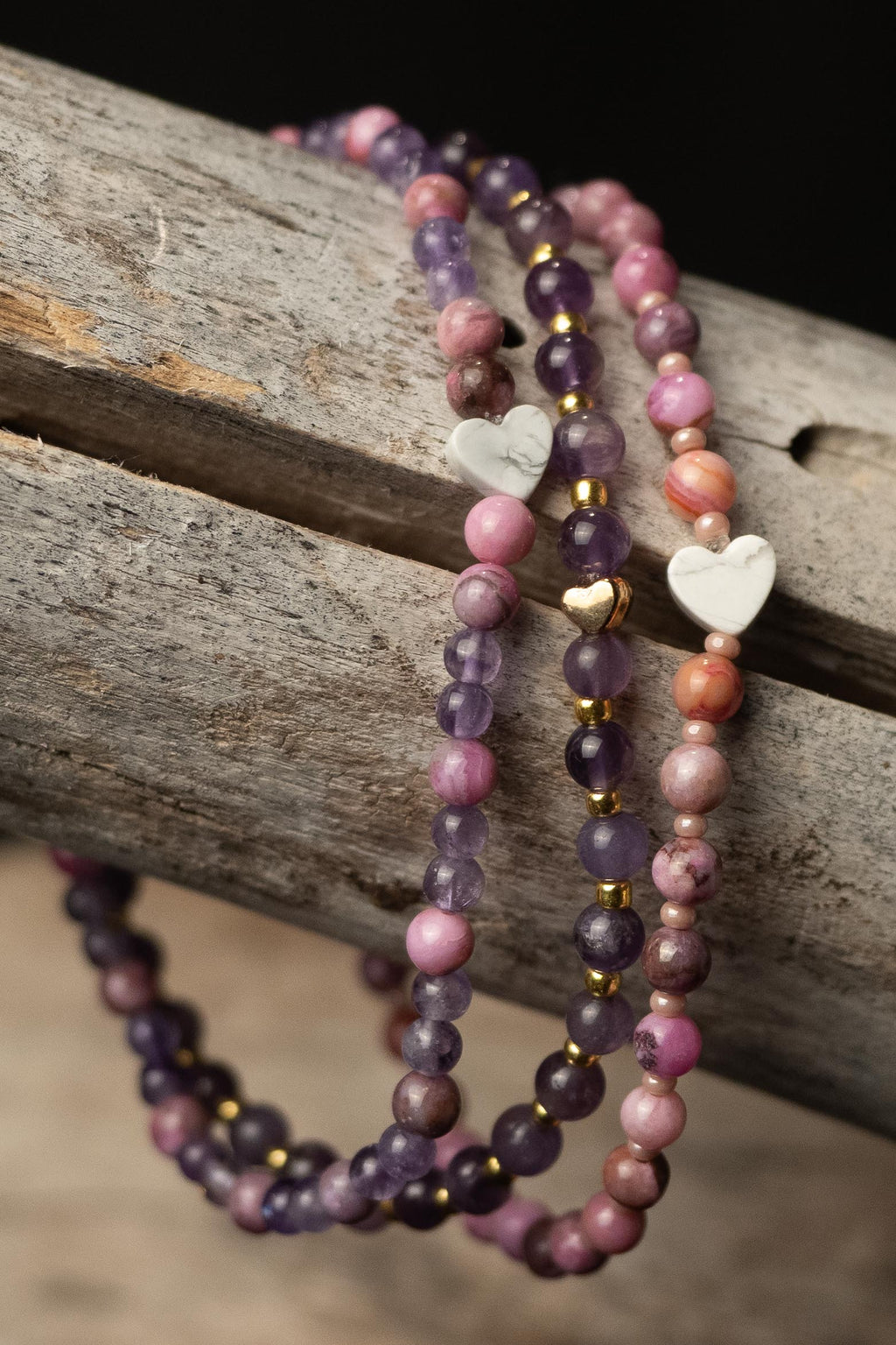 Philomena handcrafted white purple pink and gold beaded bracelet set with heart beads on a wooden surface — Amelia Heir Art