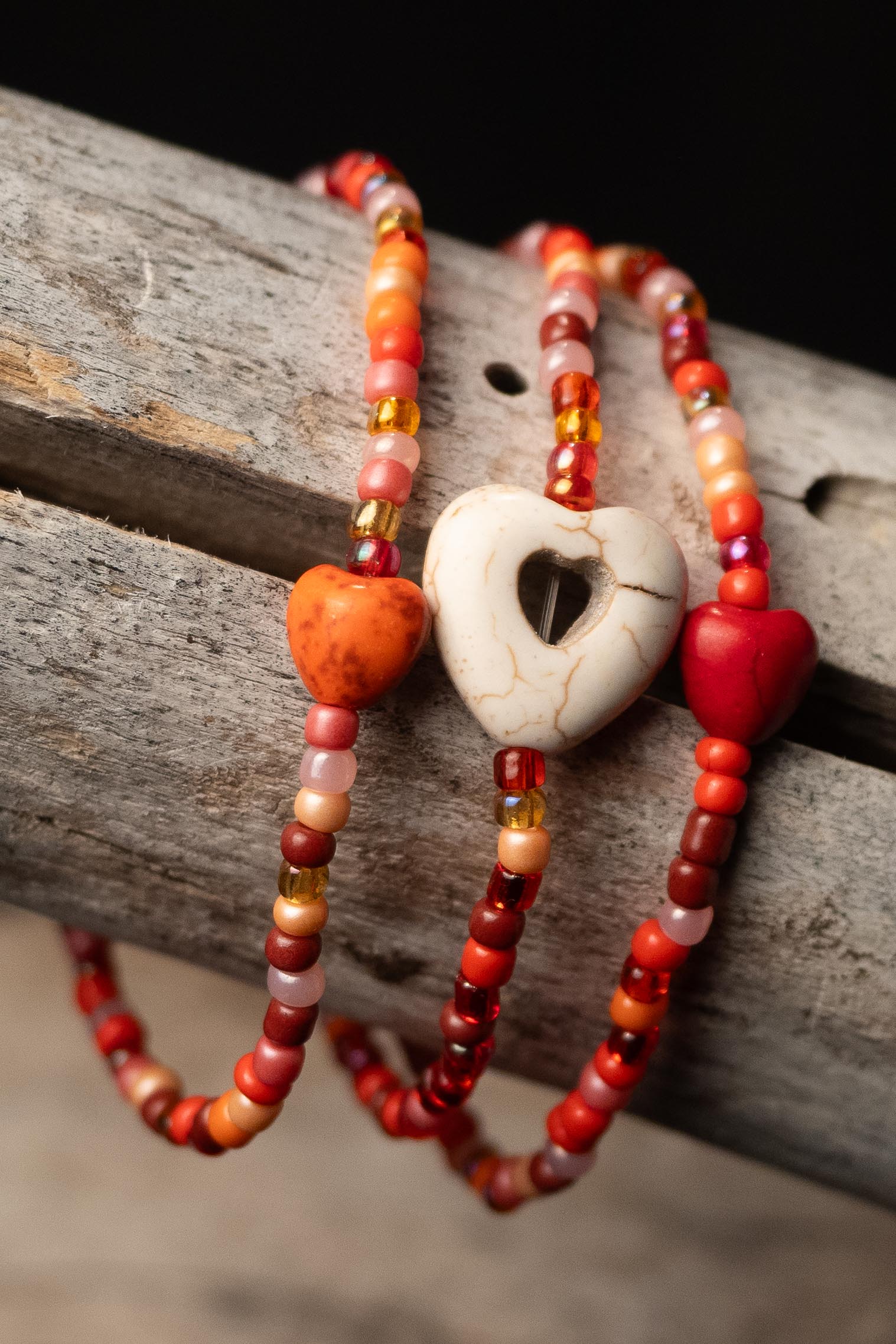 Orange beaded bracelets with heart-shaped beads on a wooden surface