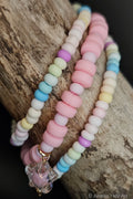 Pastel beaded bracelets with a star-shaped charm on a wooden surface