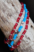 Three beaded necklaces in red and blue with silver stars on a wooden surface