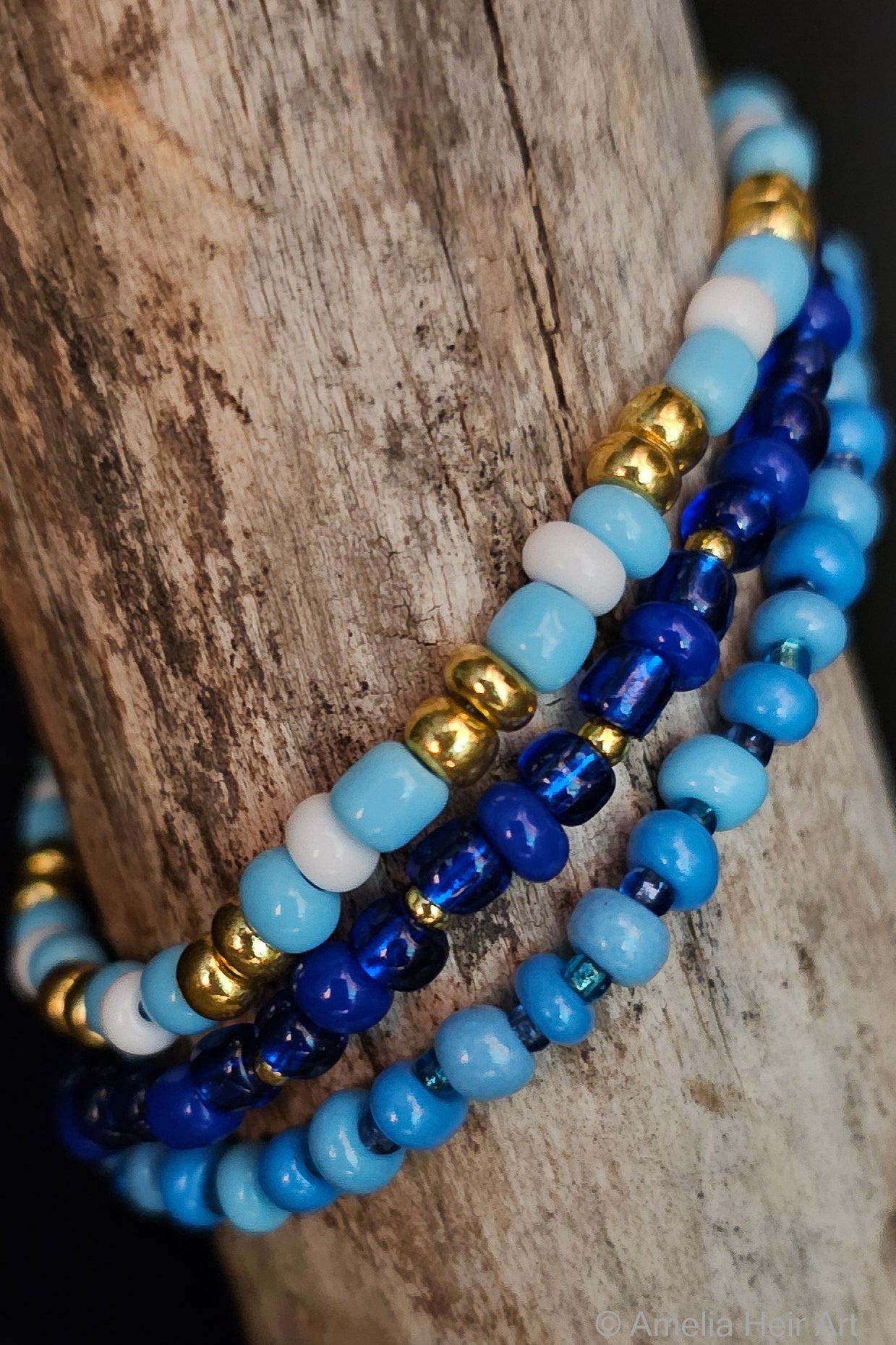 Set of blue, gold, and white beaded bracelets on a wooden surface