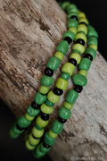 Green and black beaded bracelets on a wooden surface