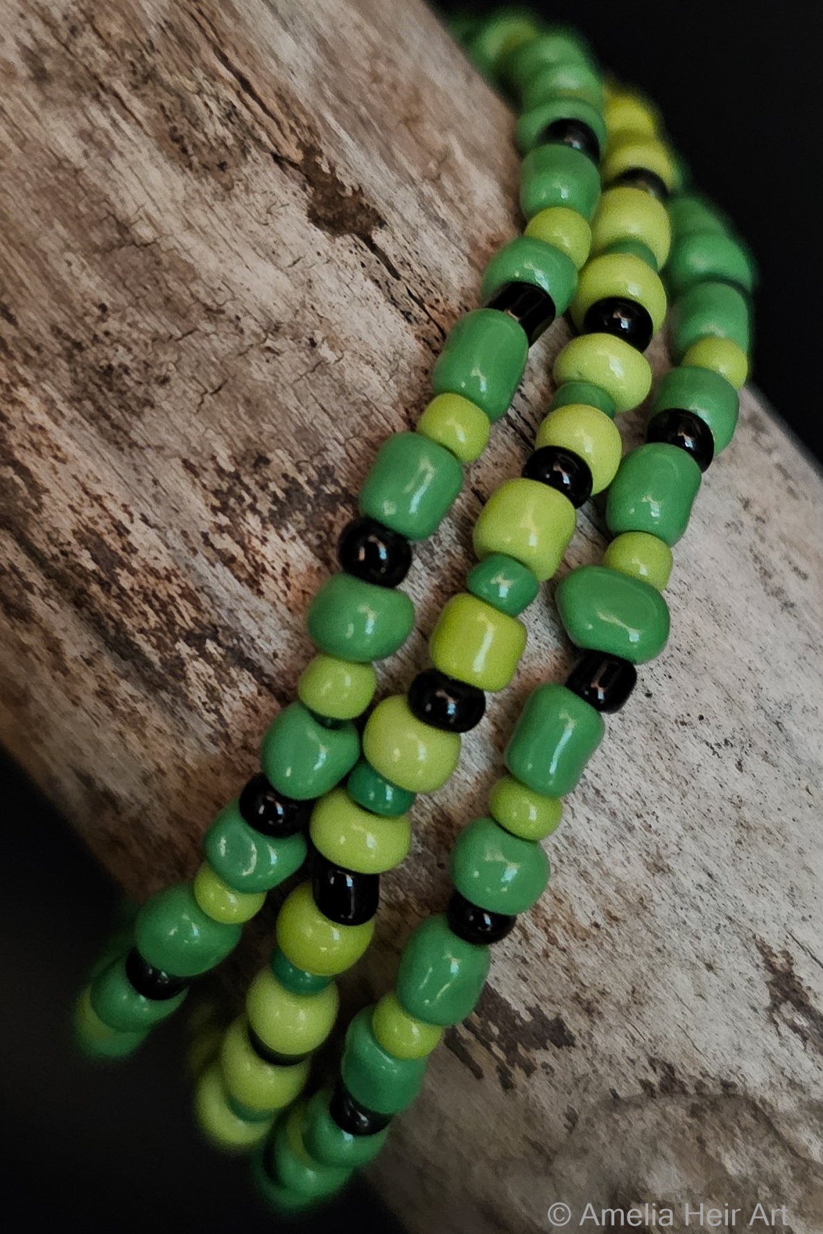 Green and black beaded bracelets on a wooden surface