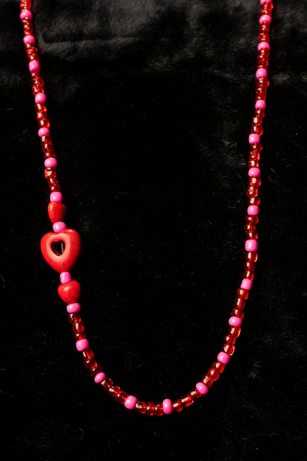 Ruby handcrafted red and pink beaded necklace with heart charm on a black background — Amelia Heir Art