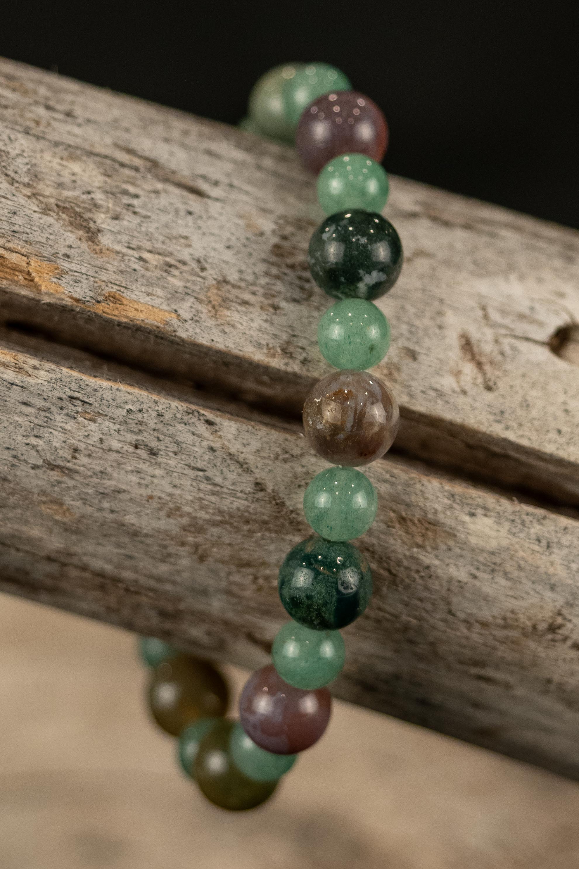 Beaded bracelet with green and brown beads on a wooden surface