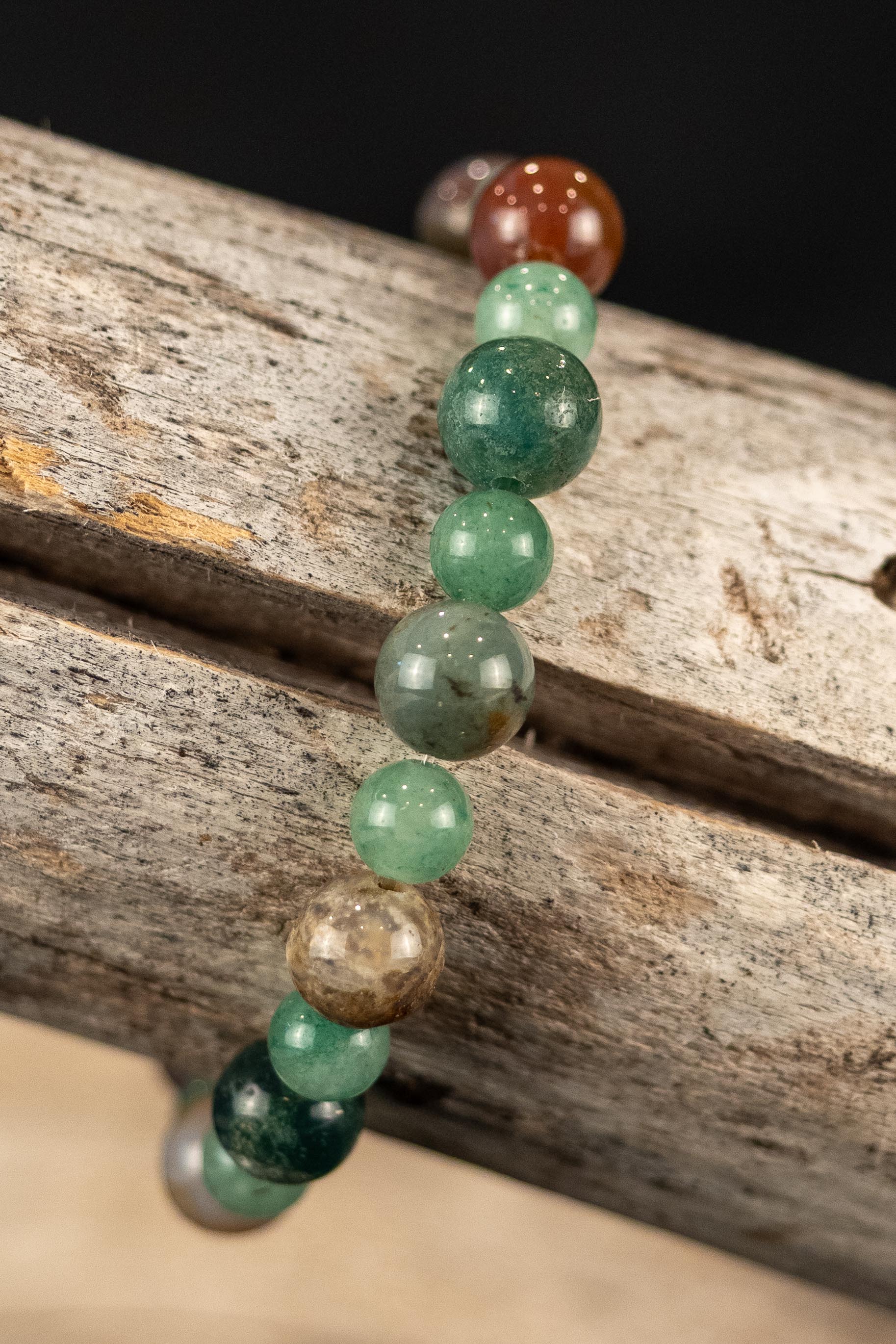 Beaded bracelet with green and brown beads on a wooden surface