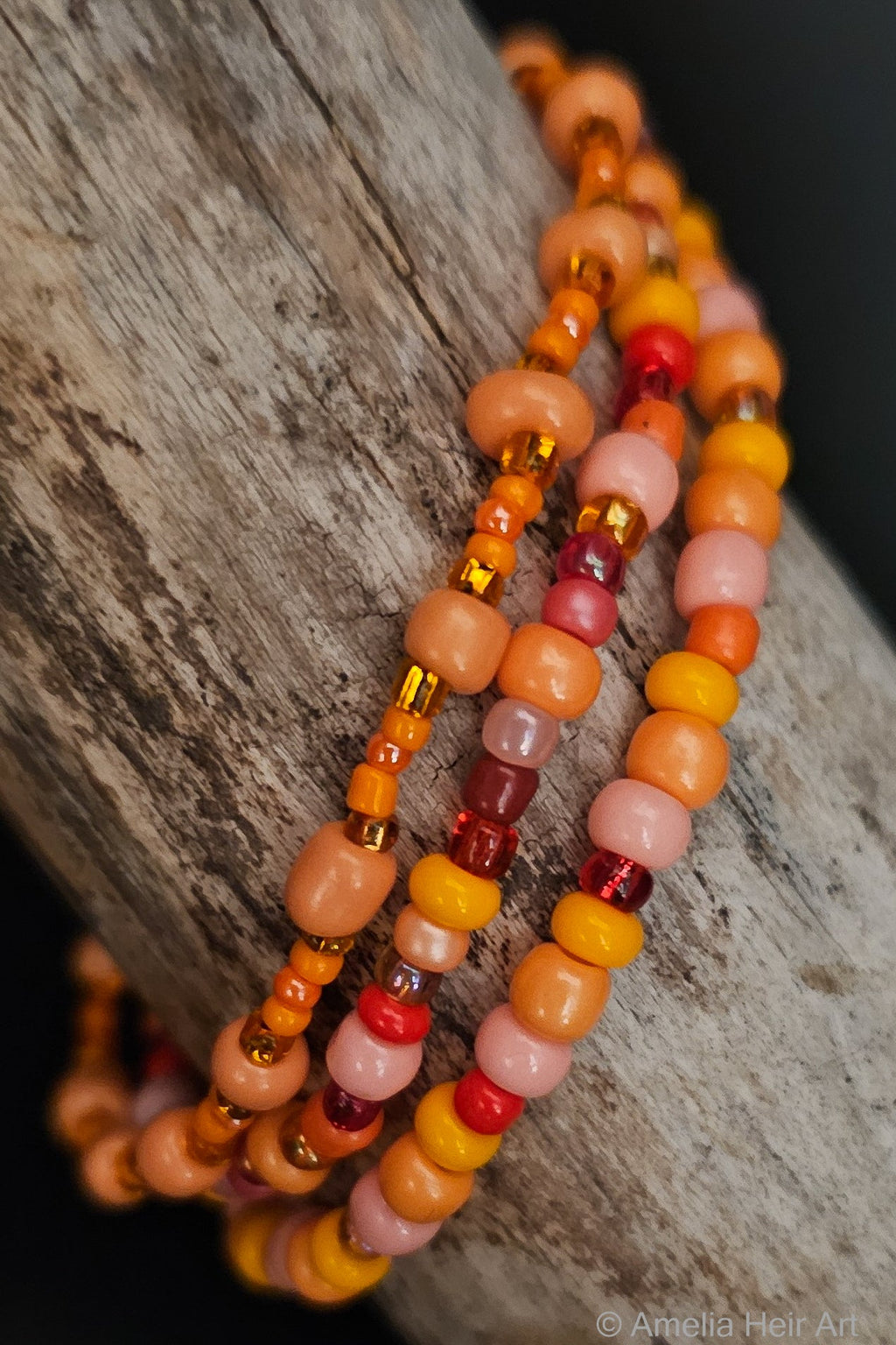 Sandy handcrafted orange beaded bracelet set on a wooden surface — Amelia Heir Art