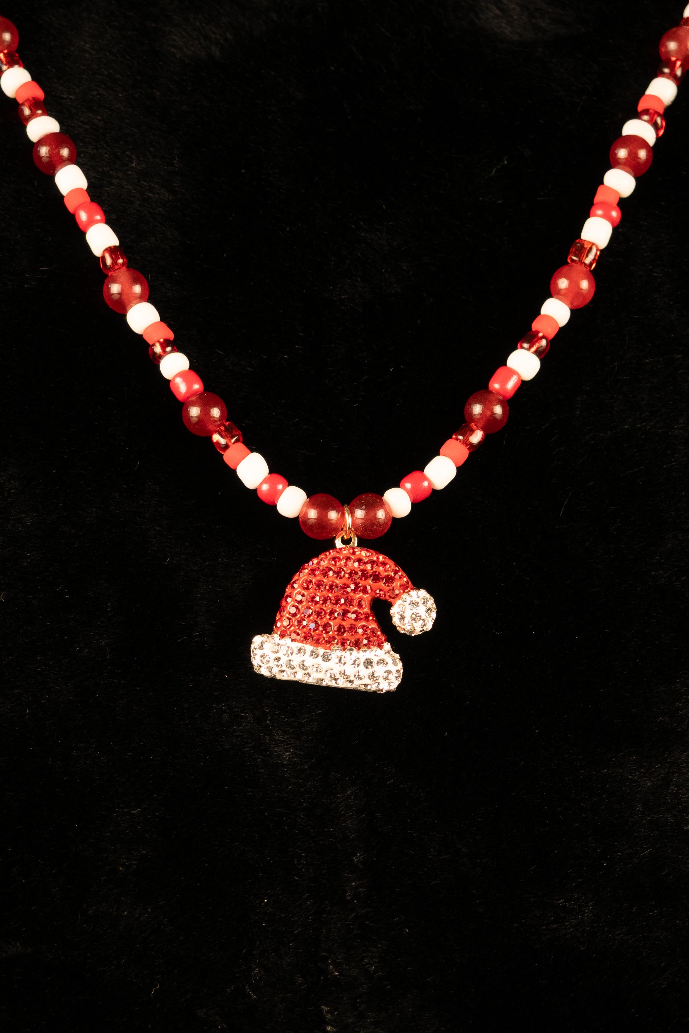 Necklace with red and white beads and a Santa hat pendant on a black background
