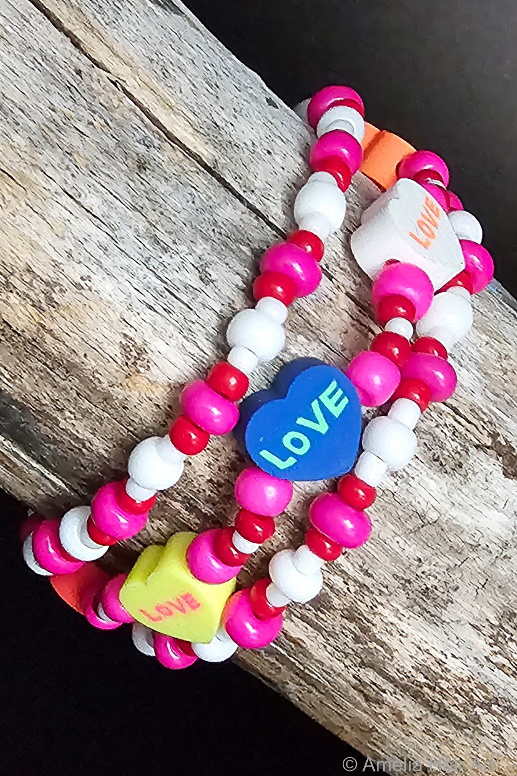 Colorful beaded bracelet with heart-shaped 'LOVE' charms on a wooden surface