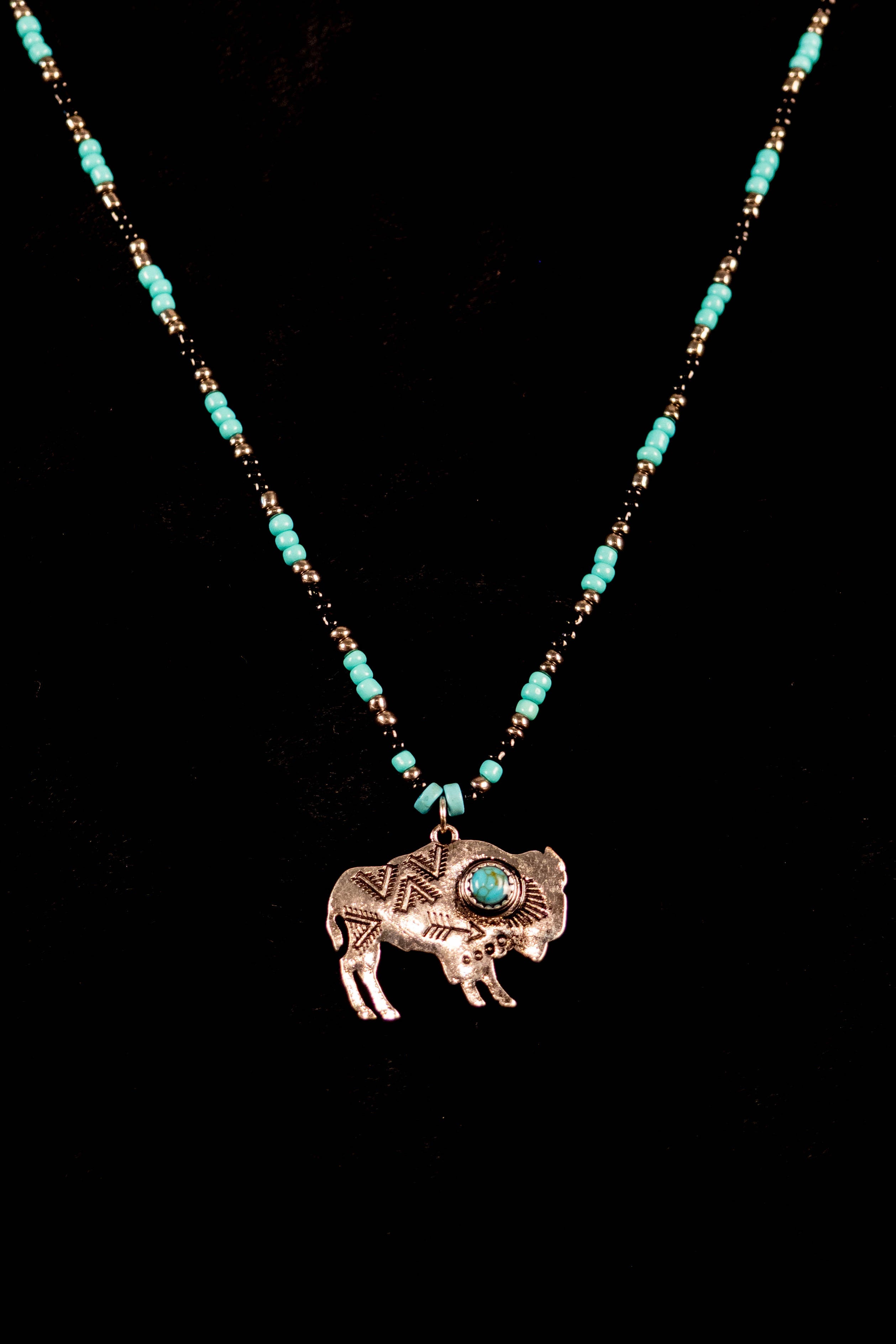 Necklace with a bison pendant and turquoise beads on a black background