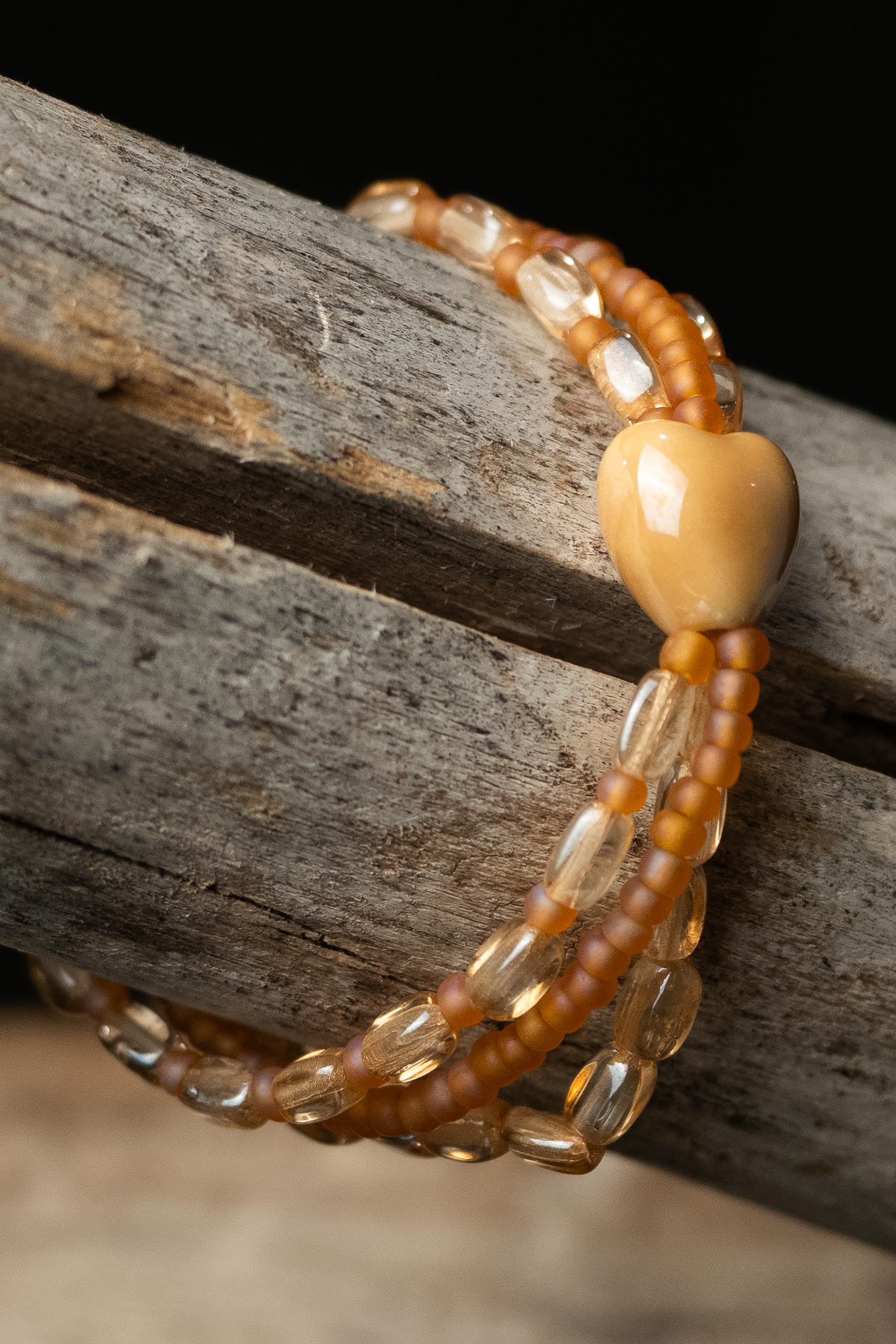 Beaded bracelet with a large central heart-bead on a wooden surface