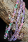 Colorful beaded bracelets with butterfly-shaped charms on a wooden surface