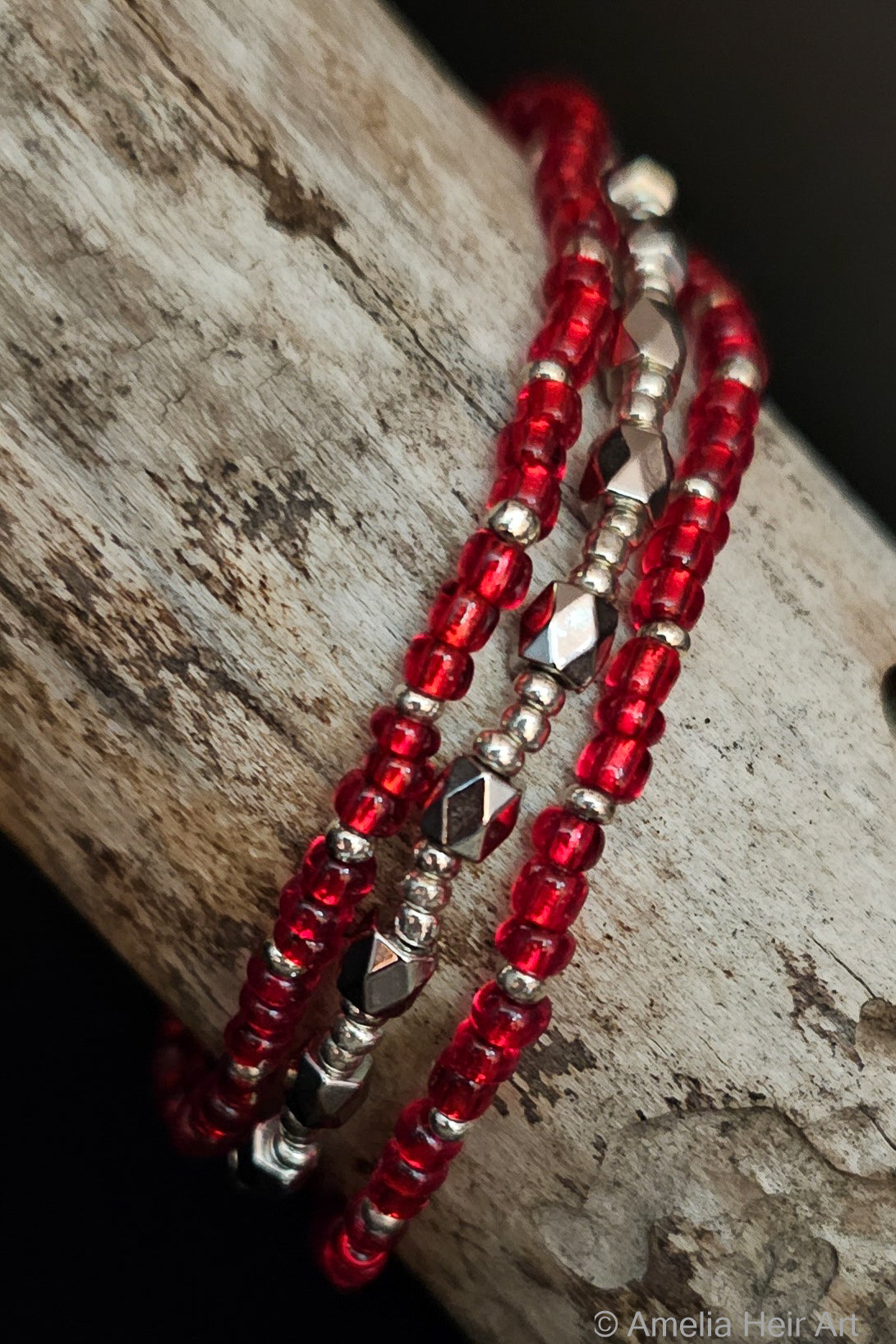 Red and silver beaded bracelets on a wooden surface
