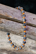 Necklace with gray and orange beads on a wooden surface