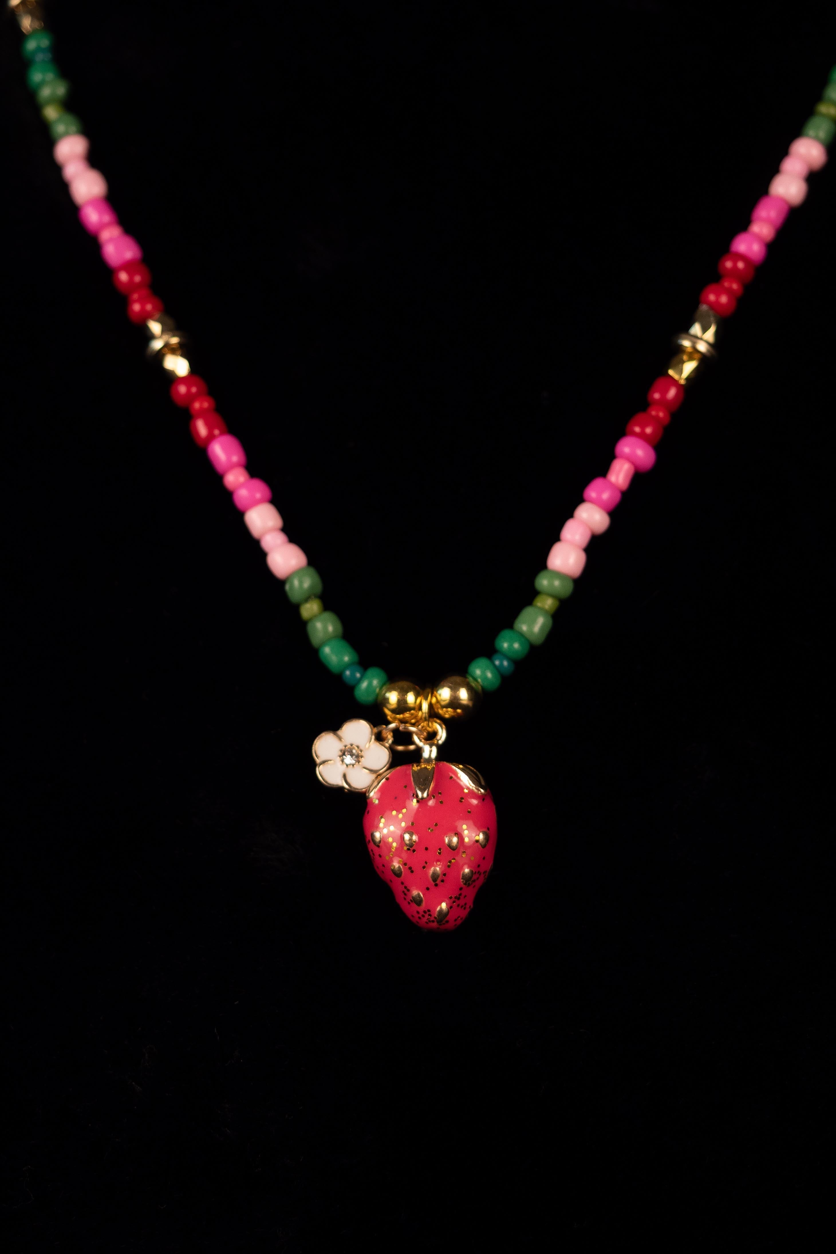 Necklace with colorful beads and a strawberry pendant on a black background