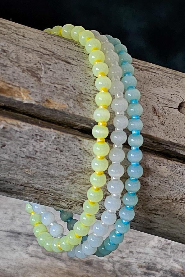 Stack of yellow, white, and blue beaded bracelets on a wooden surface