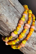 Yellow and orange beaded bracelets on a wooden surface