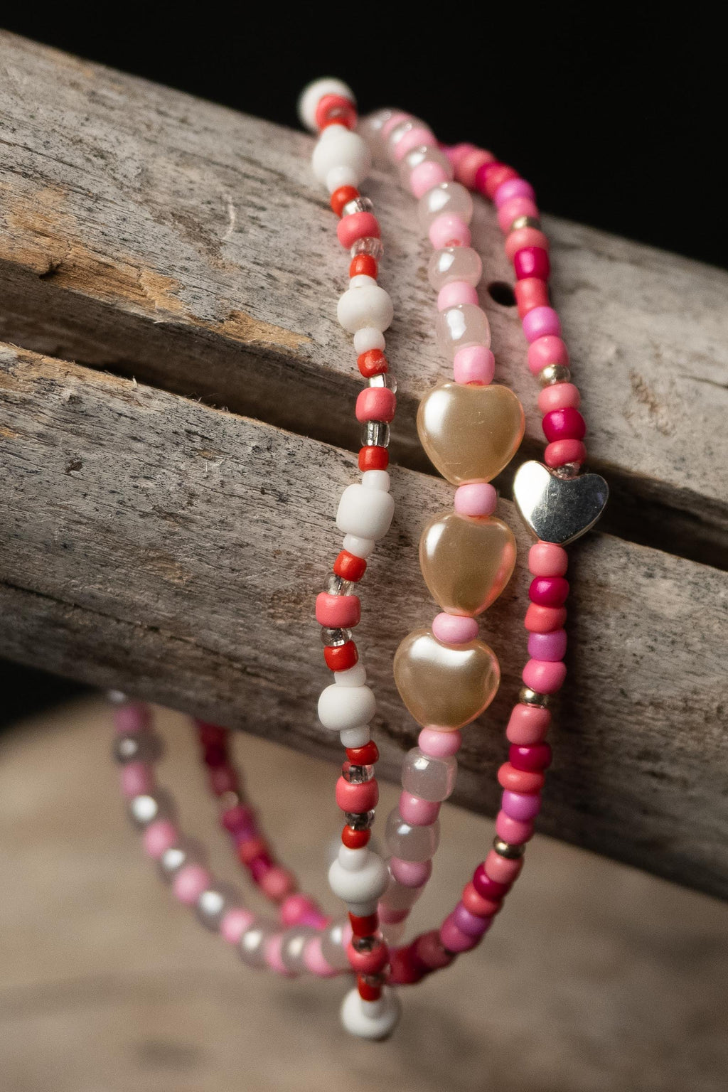 Sweetheart handcrafted white silver red and pink beaded bracelet set on a wooden surface — Amelia Heir Art