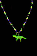 Neon green dinosaur pendant on a beaded necklace against a black background