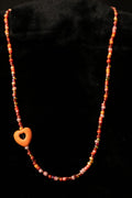 Necklace with orange beads and a heart-shaped pendant on a black background