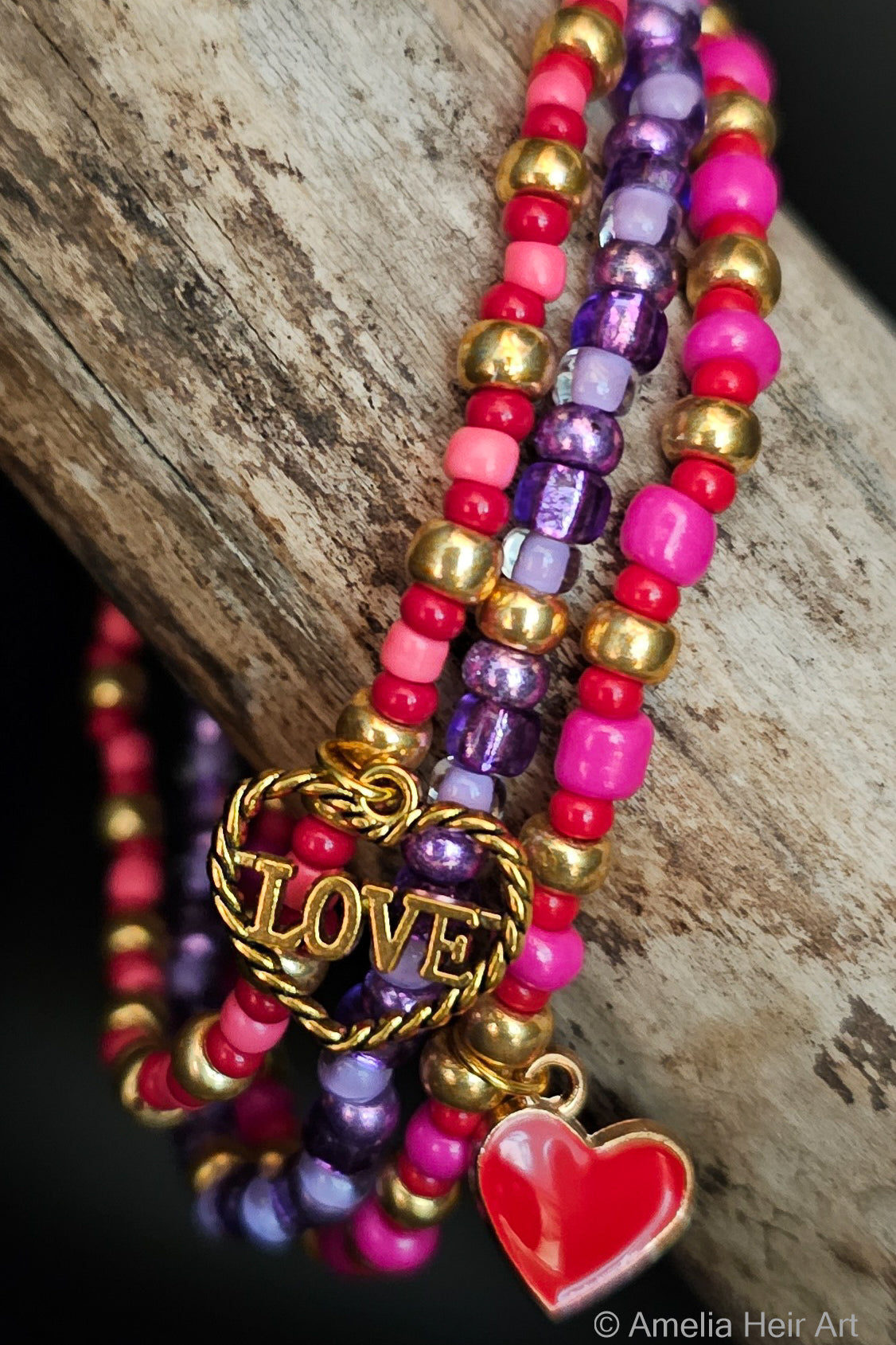 Colorful beaded bracelets with 'LOVE' and heart charms on a wooden surface.