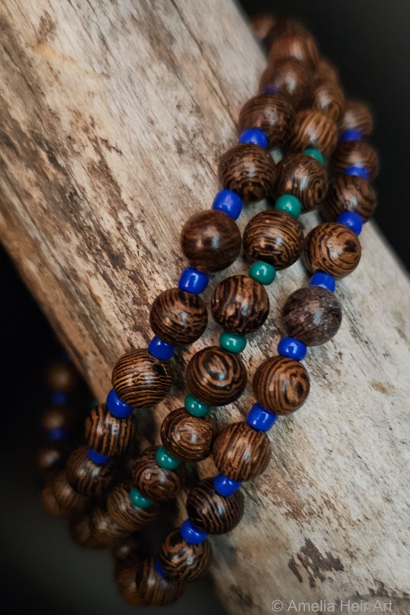 Wooden beads with blue and green accents on a wooden surface