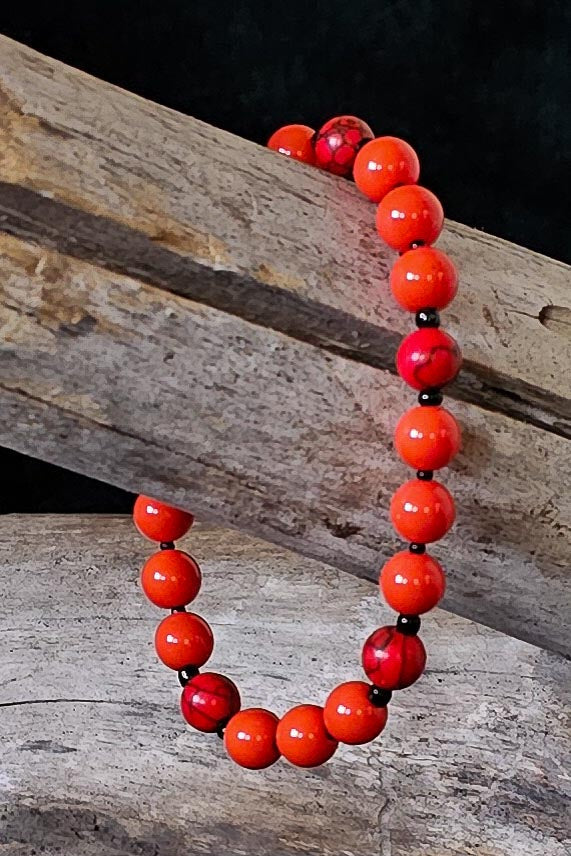 Orange and black beaded bracelet on a wooden surface.