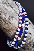 Three beaded bracelets in red, white, and blue on a wooden surface.
