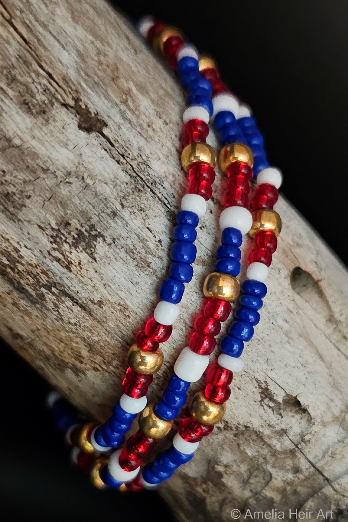 Three beaded bracelets in red, white, and blue beads on a wooden surface.