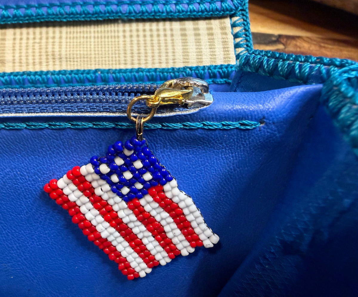 Pledge handmade zipper pull by Amelia Heir Art, featuring a red, white, and blue beaded American flag clipped to a blue wallet zipper.
