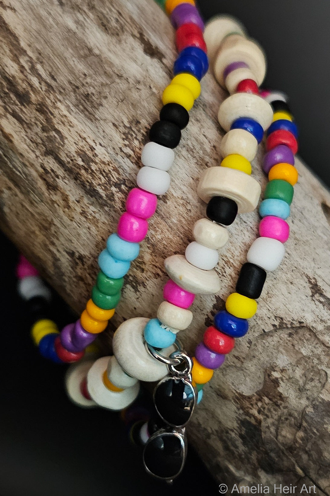 Colorful beaded bracelets with sunglasses charm on a wooden surface