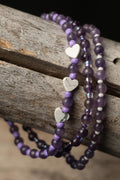 Purple beaded bracelets with white heart charms on a wooden surface